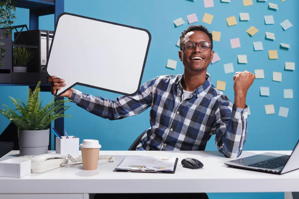 Jeune homme à son poste de travail, tenant une bulle de discussion